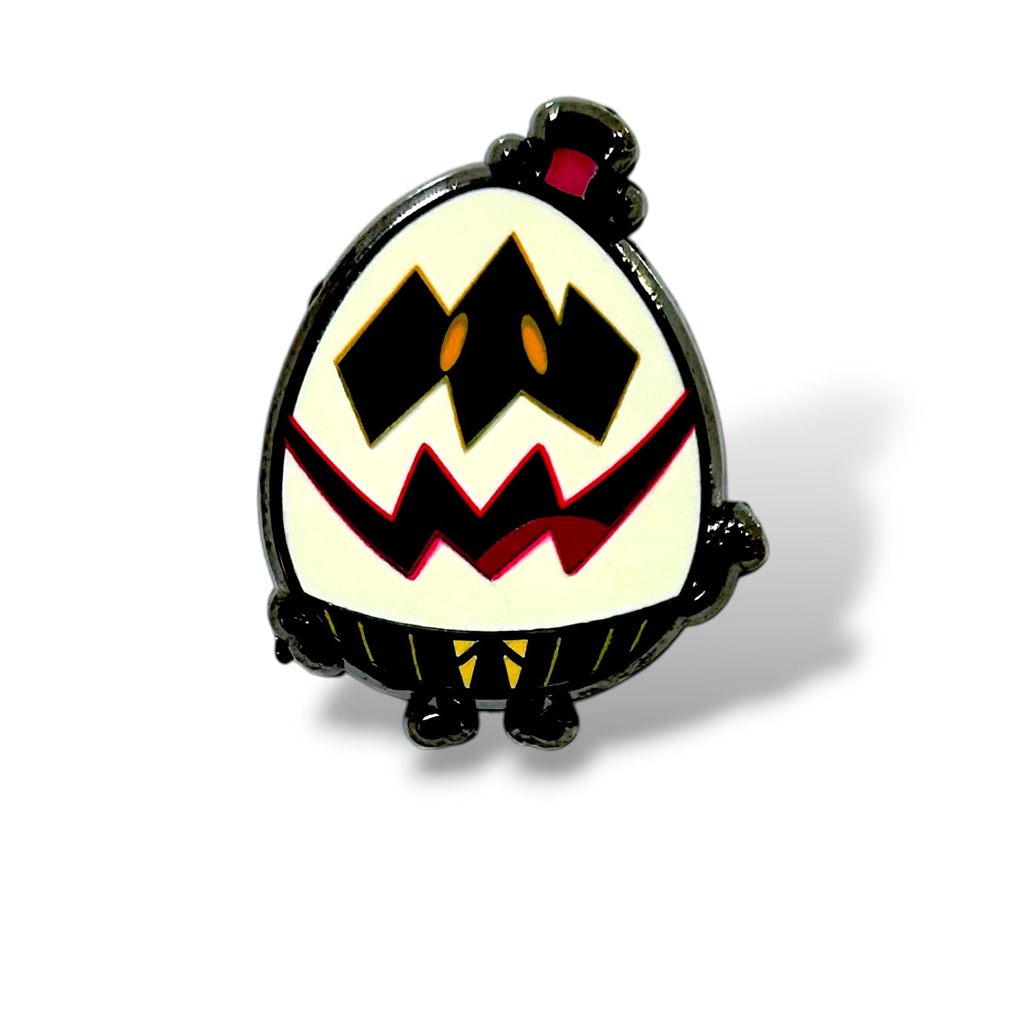 Cartoon-style enamel pin shaped like an egg character with a mischievous expression. The face is white with two large black diamond-shaped eyes containing small orange ovals, and a jagged red zigzag mouth. The character wears a tiny red-and-black top hat, has black limbs, and yellow-striped pants. The glossy finish and bold outlines give it a playful, spooky “Egg Boys” aesthetic.