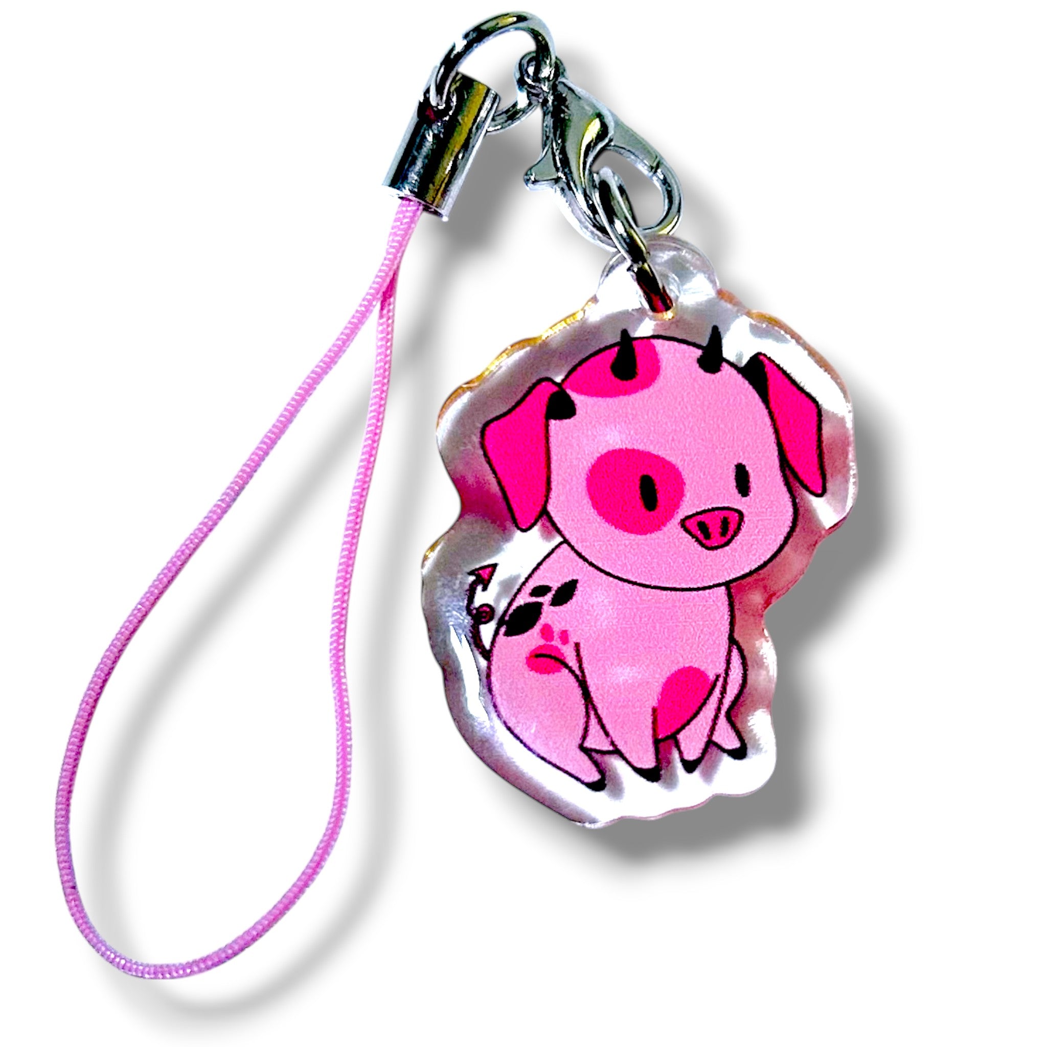 Cartoon-style acrylic keychain charm featuring a pink pig with dark pink spots, small black horns, and a cheerful expression. The pig is shown sitting upright and is attached to a pink strap with a silver clasp. The charm has a glossy finish and playful fantasy-inspired design, making it a cute and collectible accessory for fans of stylized animated pets.