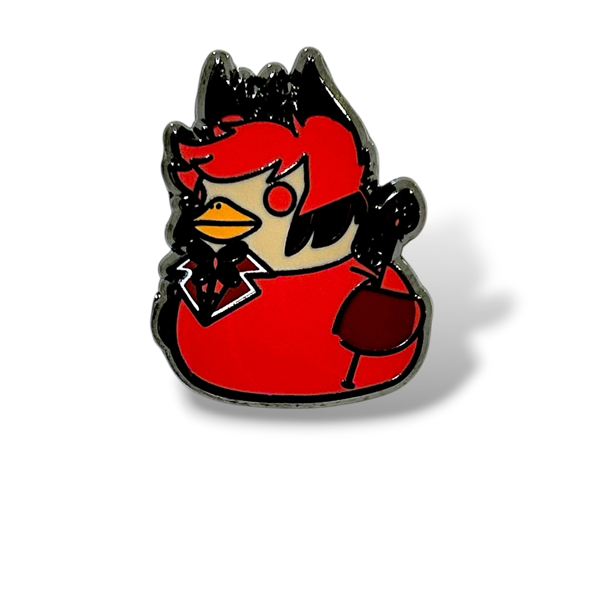 Cartoon-style enamel pin of a duck character dressed as the “Radio Demon.” The duck has spiky red hair, a red eye, and wears a red jacket with a white collar and black tie. It has black wings and holds a red wine glass, giving it a dramatic and mischievous appearance. The design is outlined in black with a glossy enamel finish, capturing a playful villain-inspired aesthetic.