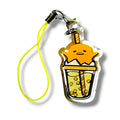 Cartoon-style keychain charm featuring an orange character with a relaxed expression, partially submerged in a bubble teacup. The cup contains several tapioca pearls and has a large straw protruding from the top. The charm is made of clear acrylic and attached to a yellow strap with a metal clasp. The design combines cozy, yolky character vibes with playful boba tea aesthetics, making it a whimsical and collectible accessory.