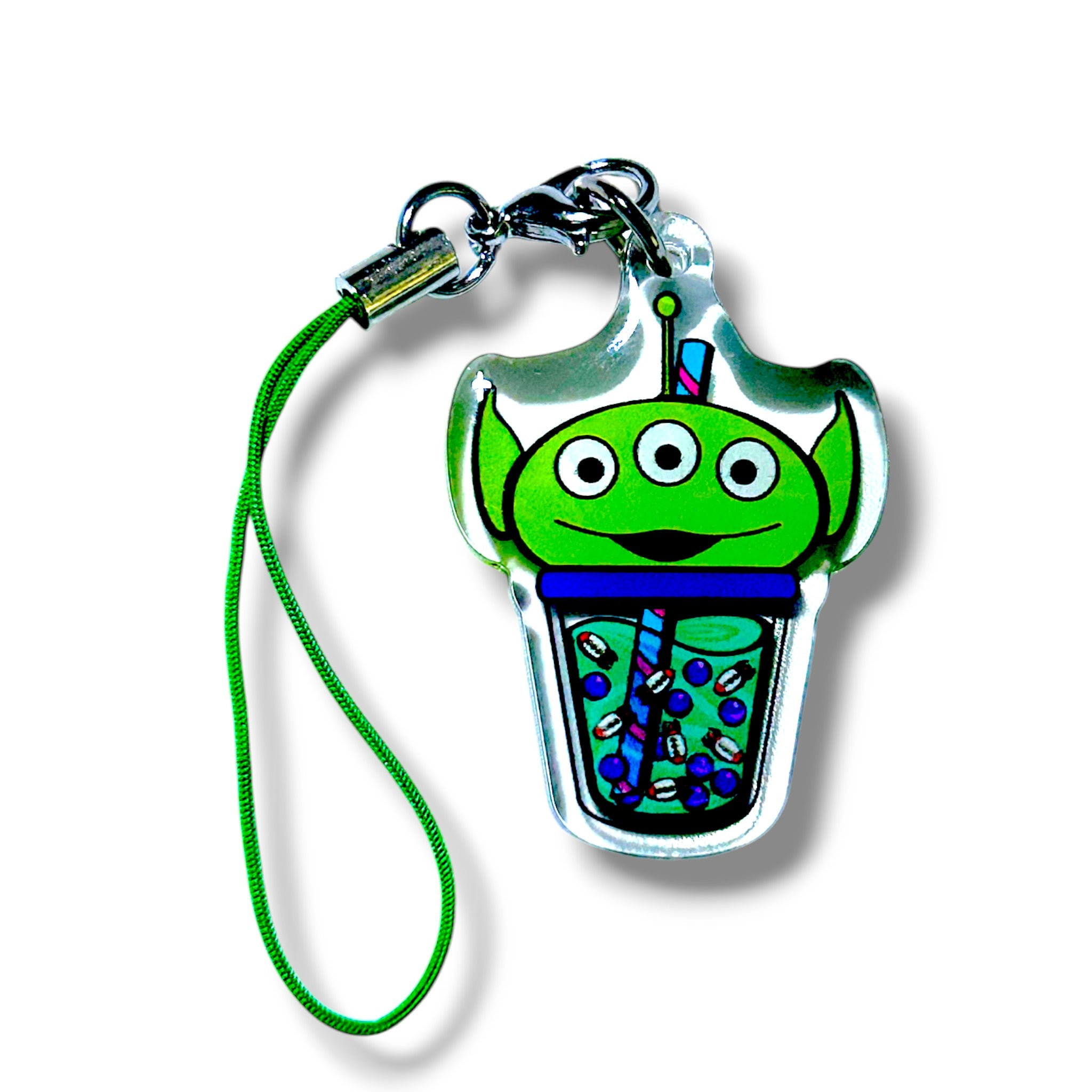 Kawaii-style keychain featuring a green alien character with three eyes, sitting inside a bubble tea cup. The alien’s head peeks out from the top of the cup, which is filled with colorful tapioca pearls and topped with a blue-striped straw. The charm is attached to a green strap with a metal clasp. The design is playful and vibrant, blending sci-fi and boba culture into a fun, collectible accessory.