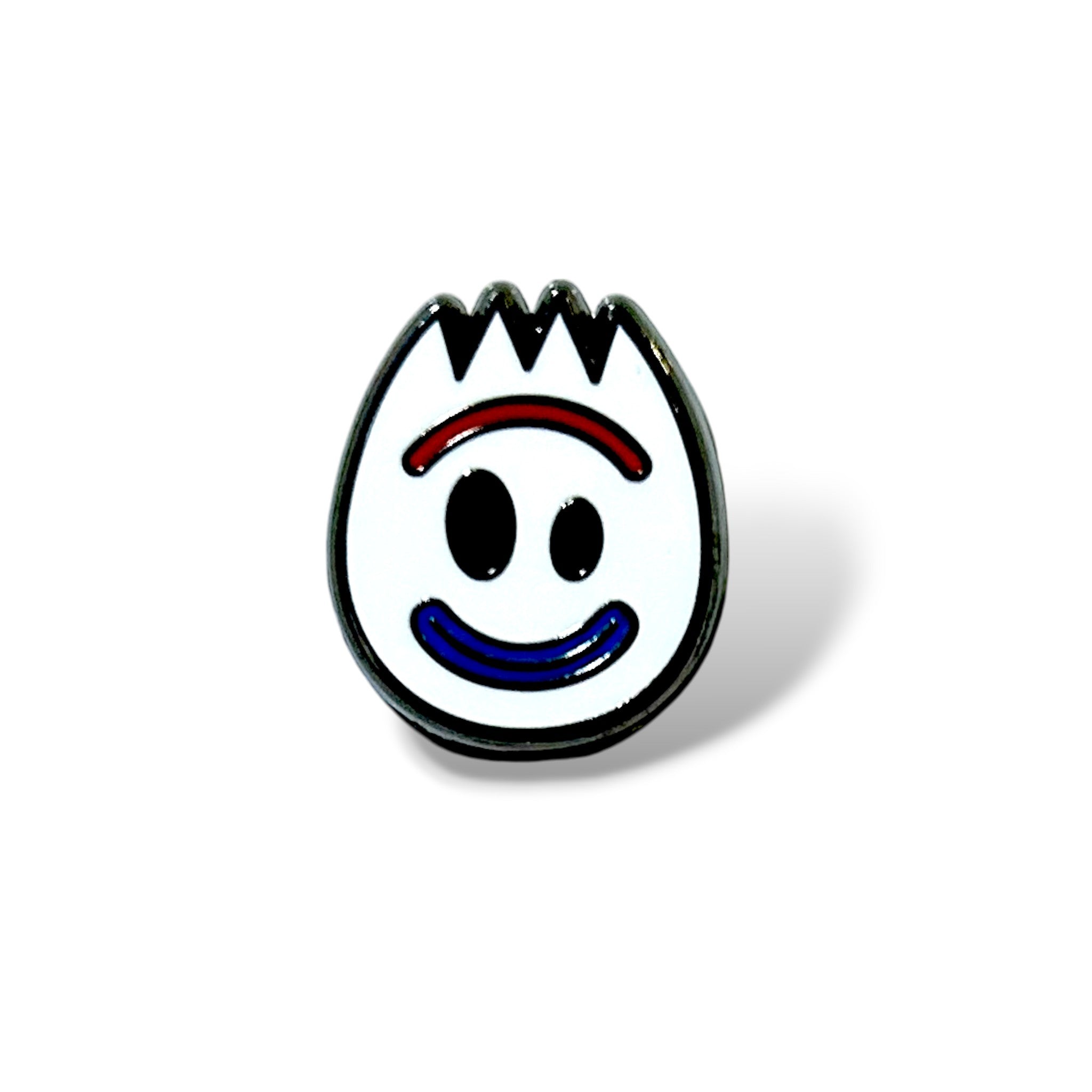 Cartoon-style enamel pin featuring a white spork face with black oval eyes, a red curved eyebrow line, and a blue smiling mouth; outlined in black with a jagged top edge, designed in a playful, simplified style.