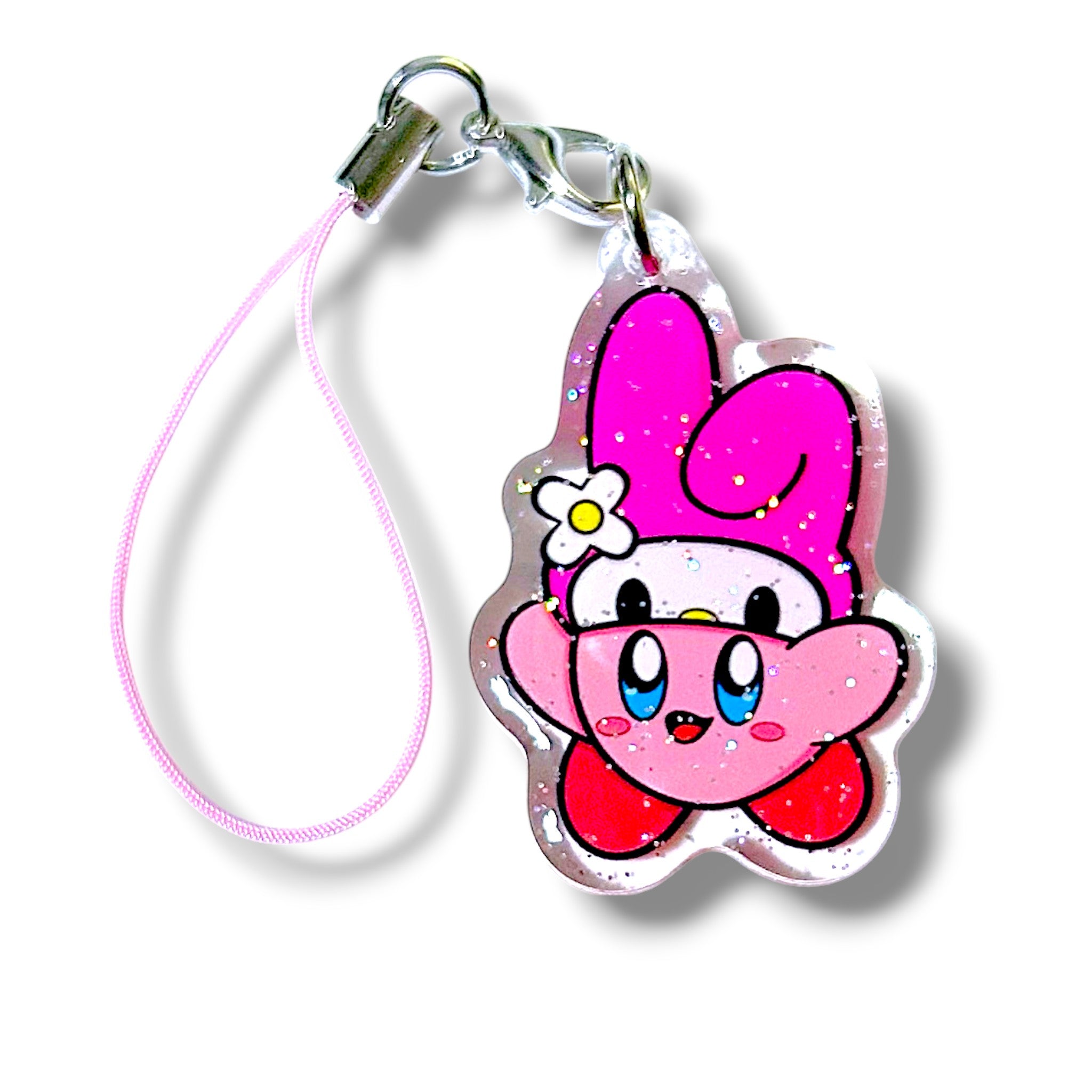 Kawaii-style keychain charm featuring a mashup character inspired by Kirby and My Melody. The character has Kirby’s round pink body, blue eyes, and red feet, paired with My Melody’s signature pink bunny hood and a white flower with a yellow center on the side. The charm is made of clear acrylic with embedded glitter, giving it a sparkly finish. It’s attached to a pink strap with a metal clasp. The design blends gamer nostalgia with Sanrio sweetness, making it a playful and collectible accessory.