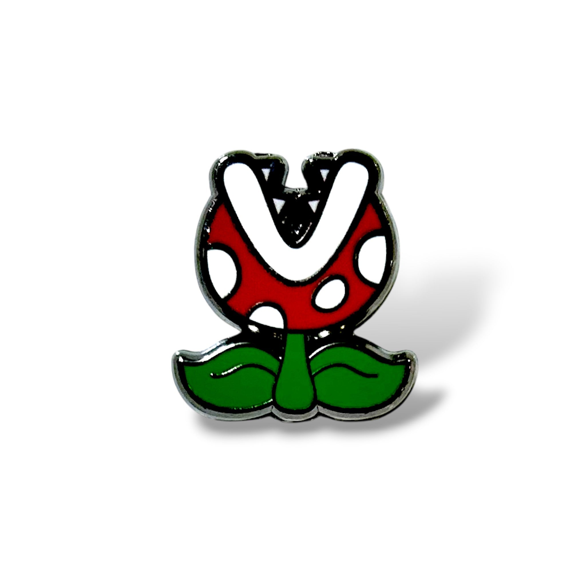 Enamel pin featuring a cartoon-style red plant head with white spots, a wide white V-shaped mouth, and green leaves at the base; outlined in black and designed with a playful, glossy finish inspired by classic gaming characters.