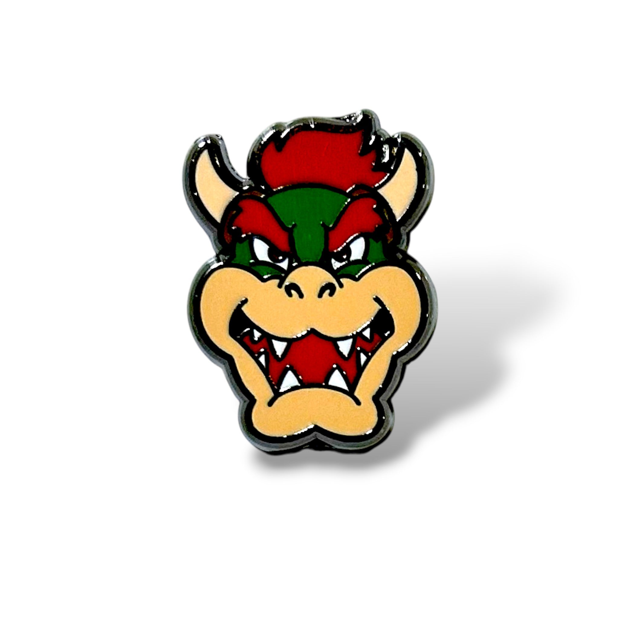 Enamel pin featuring a fierce green and beige spiked king face with sharp teeth, red eyes, and fiery details; outlined in black with bold colors, designed in a cartoon style inspired by classic gaming villains.