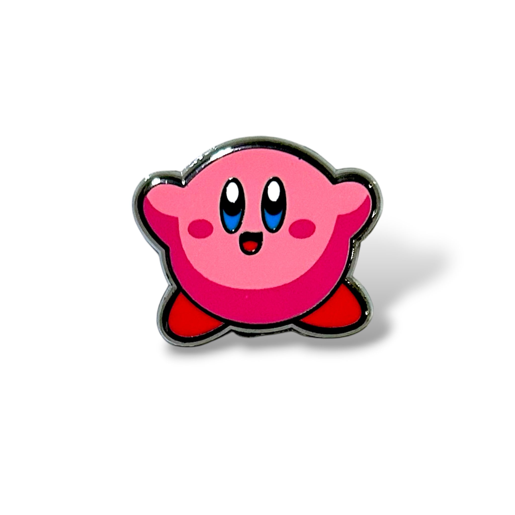 Enamel pin featuring a cheerful pink round hero character with big blue eyes, red feet, and rosy cheeks, smiling with arms raised in a playful pose; glossy finish with bold outlines, inspired by classic gaming icons.