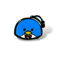 Enamel pin of a cartoon-style blue penguin with small black eyes, a yellow beak, and a red bow tie over a white shirt collar. The penguin wears a tilted white and green top hat, and the design features a shiny black outline—capturing a whimsical, kawaii aesthetic inspired by Tuxedo Sam from Sanrio.