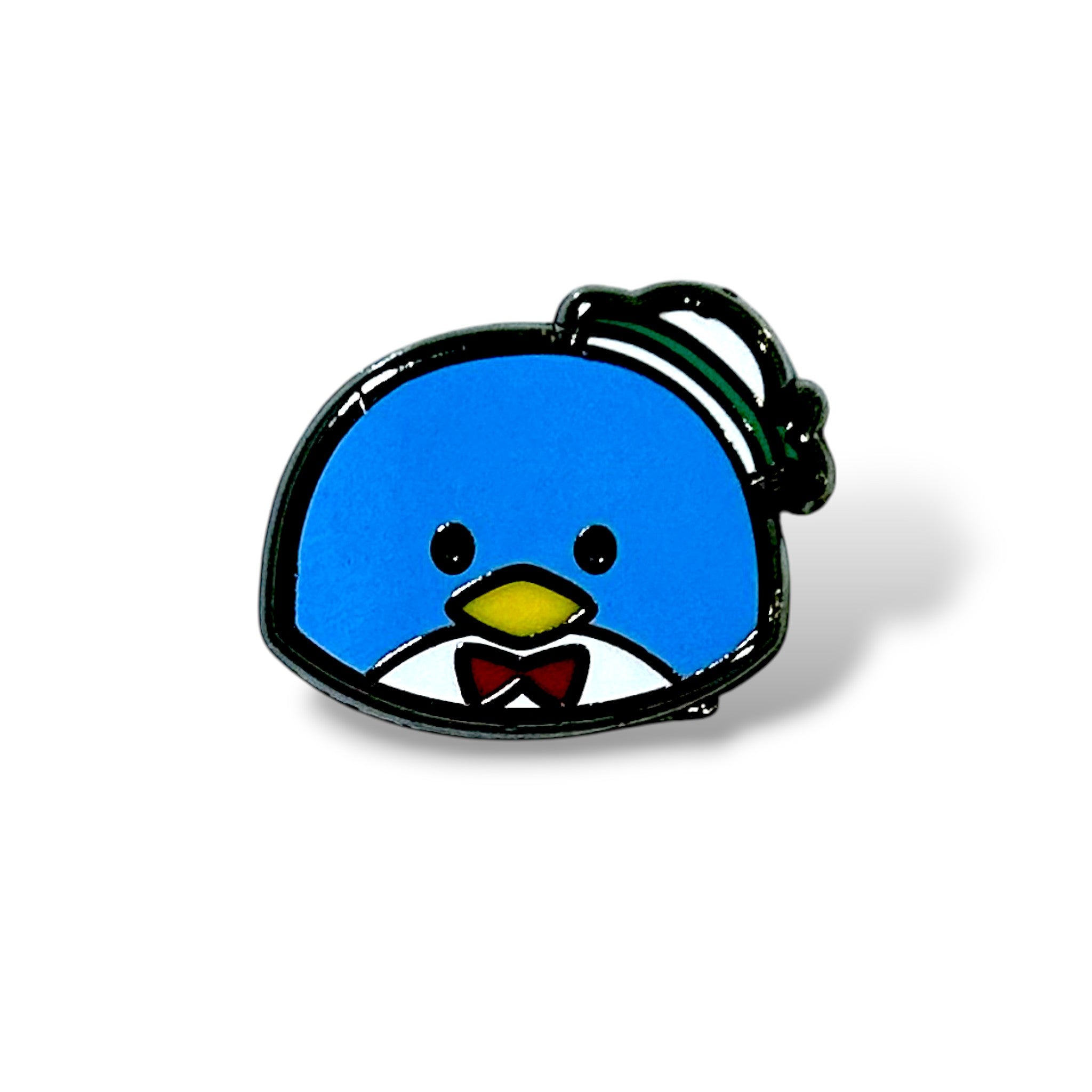 Enamel pin of a cartoon-style blue penguin with small black eyes, a yellow beak, and a red bow tie over a white shirt collar. The penguin wears a tilted white and green top hat, and the design features a shiny black outline—capturing a whimsical, kawaii aesthetic inspired by Tuxedo Sam from Sanrio.