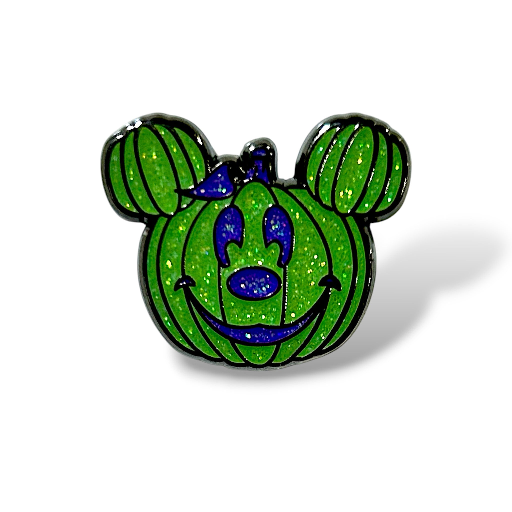 Enamel pin shaped like a glittery green pumpkin with vertical black ridges, styled with round mouse ears and a cheerful blue face featuring eyes, nose, and a smiling mouth; accented with a small blue bow on one ear, combining Halloween and cartoon-inspired aesthetics.