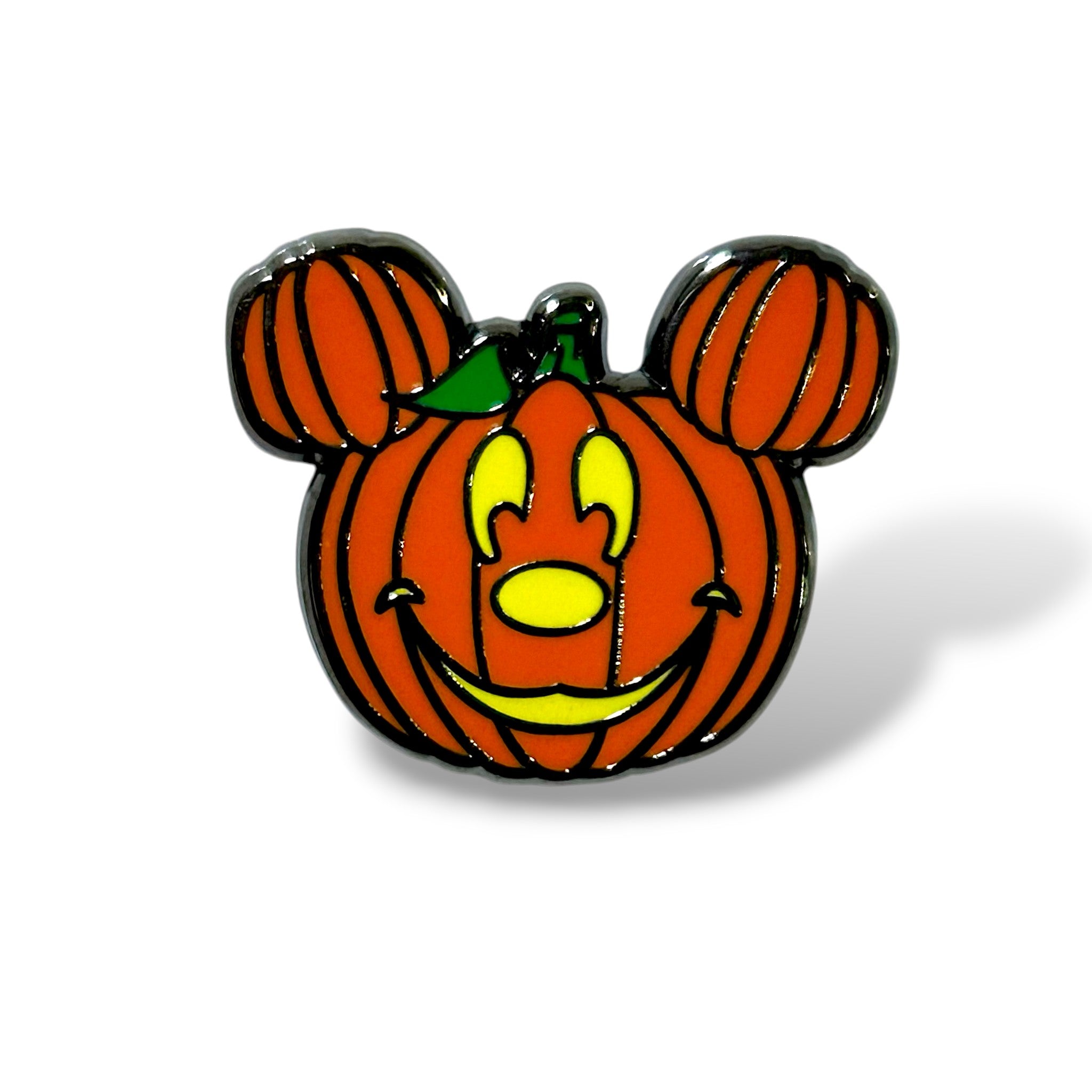 Enamel pin shaped like an orange pumpkin with vertical black ridges and round mouse ears, featuring cheerful yellow facial features including eyes, nose, and a smiling mouth; topped with a green stem and designed in a playful cartoon style that blends Halloween and classic character aesthetics.