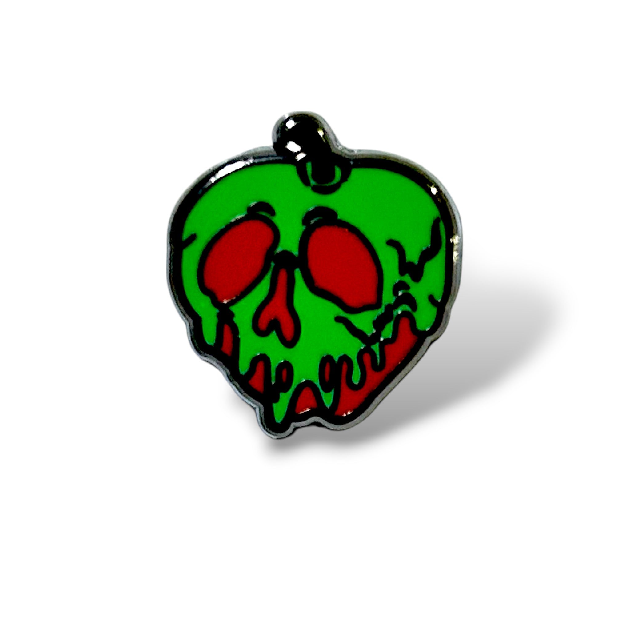 Enamel pin shaped like a green skull with red eye sockets and a red mouth, dripping over a red apple base with a black stem; designed in a spooky, cartoon style inspired by villainous fairy tale motifs and Halloween aesthetics.