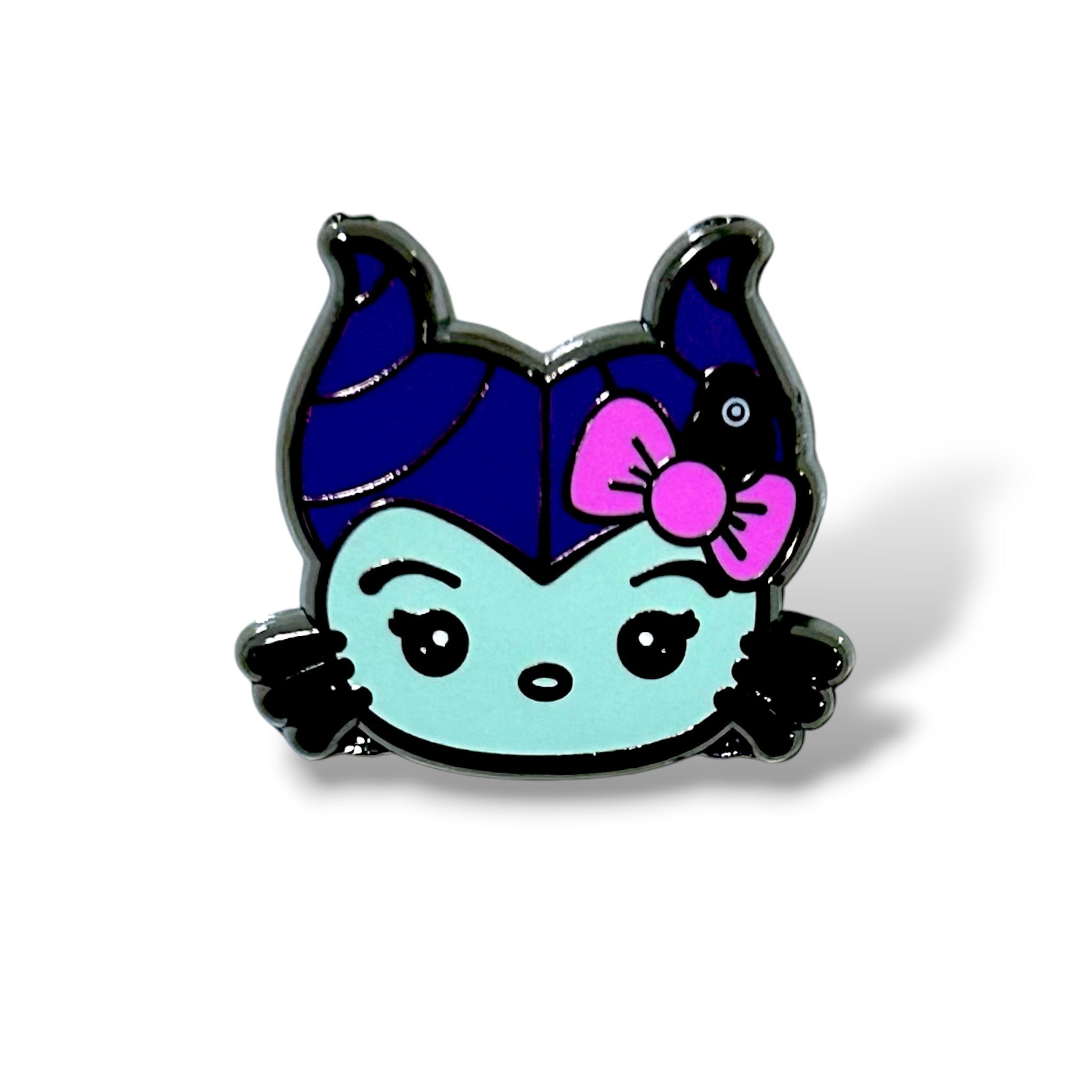 Enamel pin featuring a chibi-style cat character dressed as Maleficent, with a light blue face, dark blue and purple horned headpiece, pink bow, and a small black bird perched on the bow; designed in a cute, spooky cartoon style inspired by Sleeping Beauty villains.