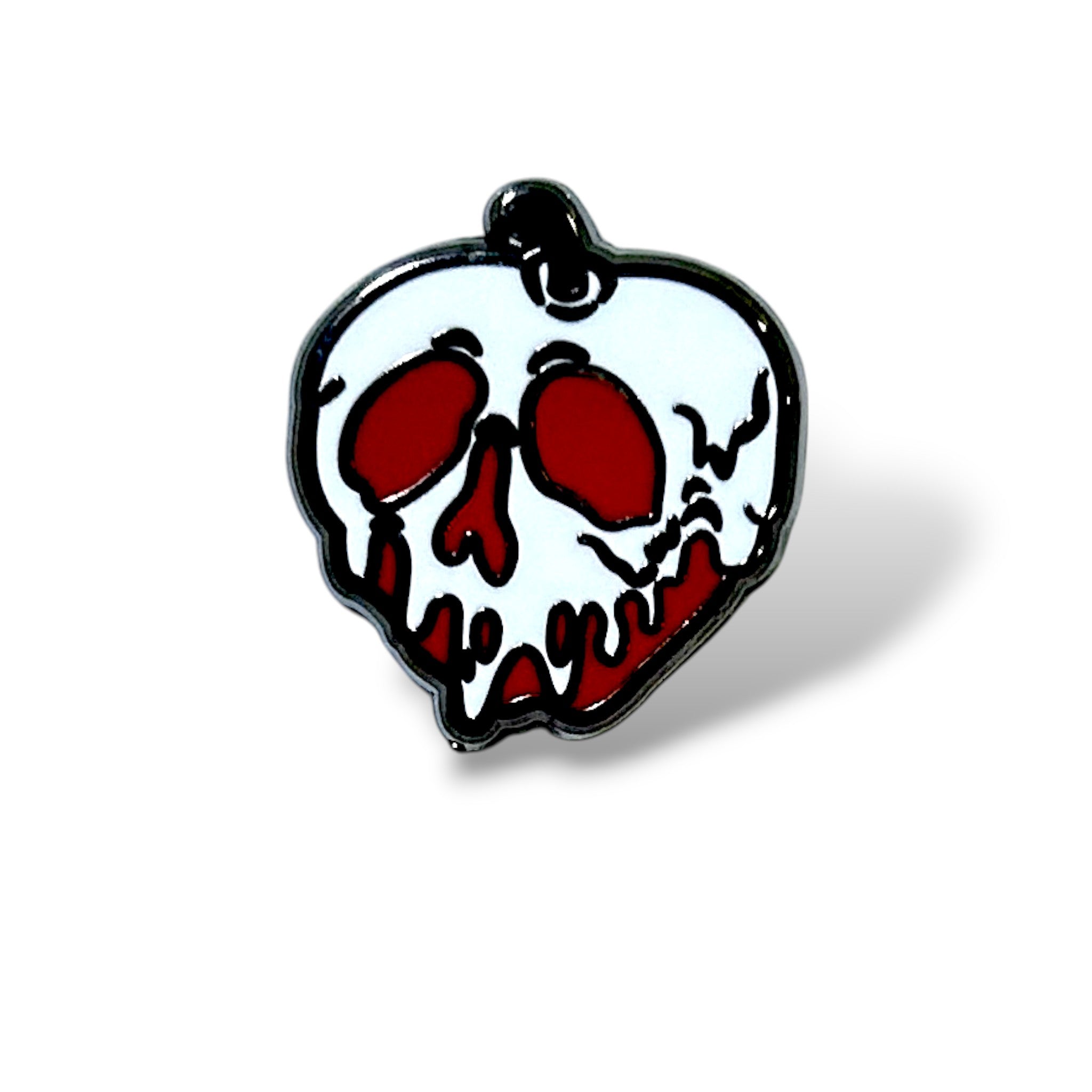 Enamel pin shaped like a red apple with a white skull overlay, featuring hollow eye sockets and a dripping design that blends into the red base; outlined in black with a loop at the top, evoking a spooky, villain-inspired aesthetic.